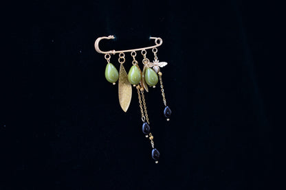 Nature-inspired gold brooch with green glass beads